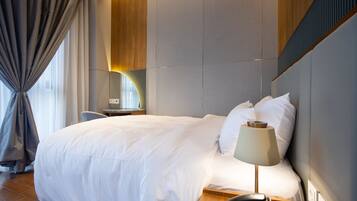 Hotelkamer met een groot bed, nachtkastje met een lamp, telefoon en uitzicht op de stad door een raam met gordijnen.