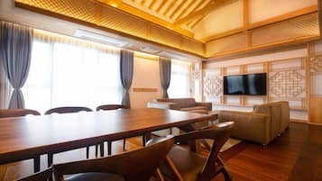 Uma sala de conferências com uma mesa de madeira, cadeiras, um sofá e uma televisão na parede.