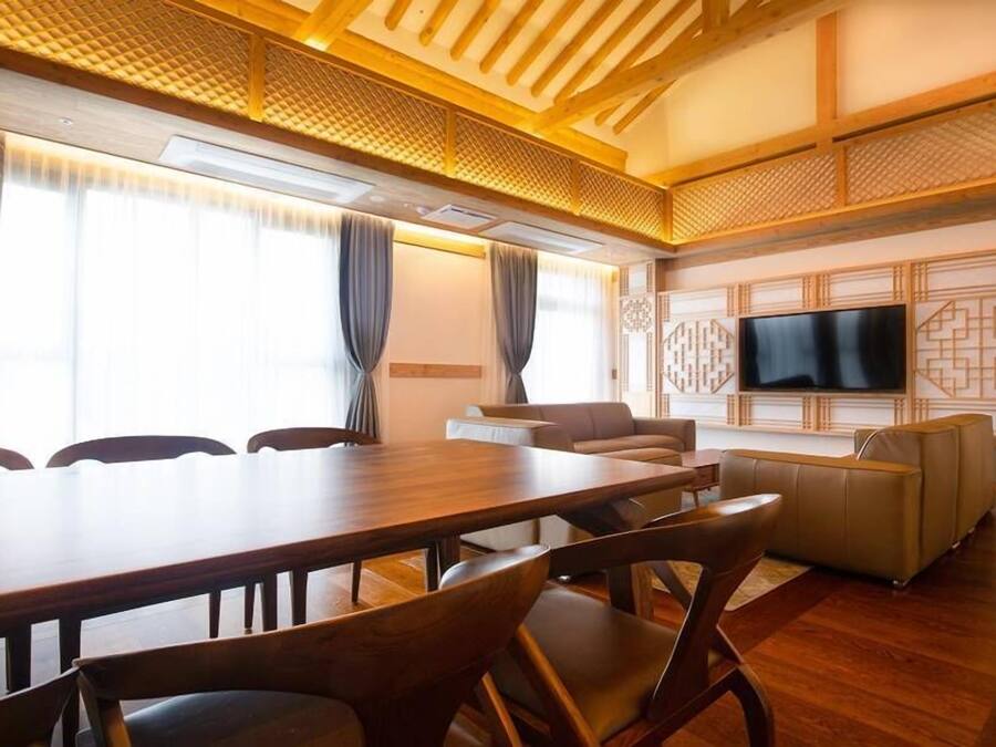 Uma sala de conferências com uma mesa de madeira, cadeiras, um sofá e uma televisão na parede.