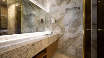 A modern bathroom with a marble vanity, a large mirror, and a glass shower enclosure.