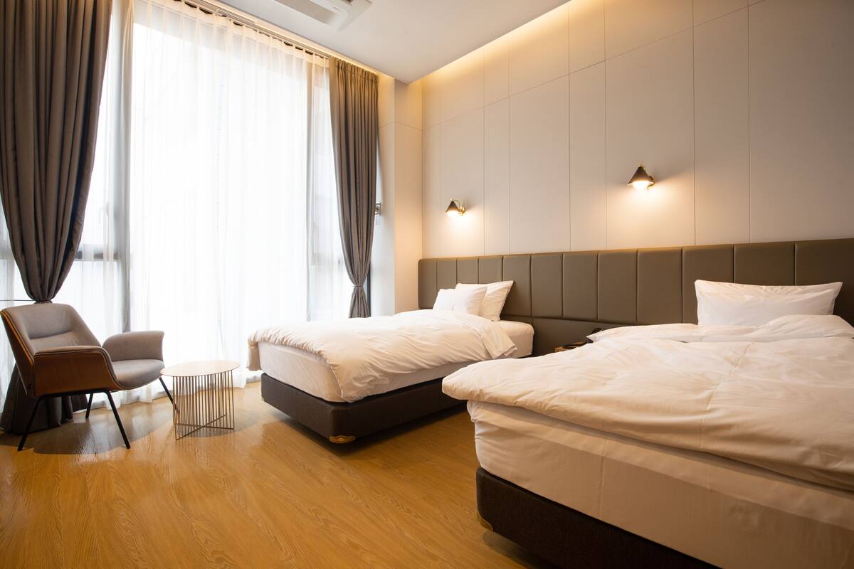 Una habitación de hotel con dos camas, una silla y una mesita.