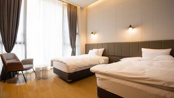 Ein Hotelzimmer mit zwei Betten, einem Sessel und einem kleinen Tisch.