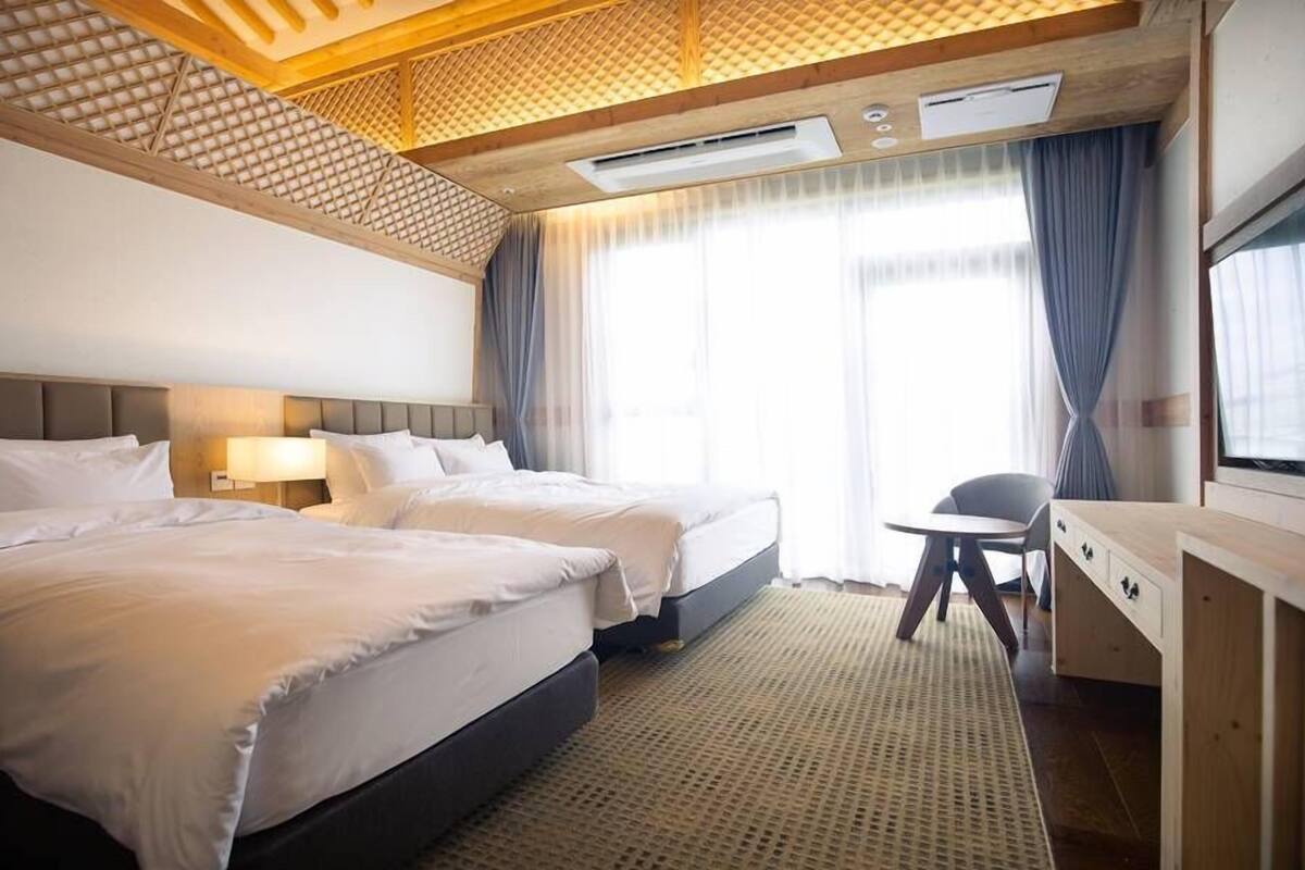 Habitación de hotel con dos camas, un escritorio y una silla.