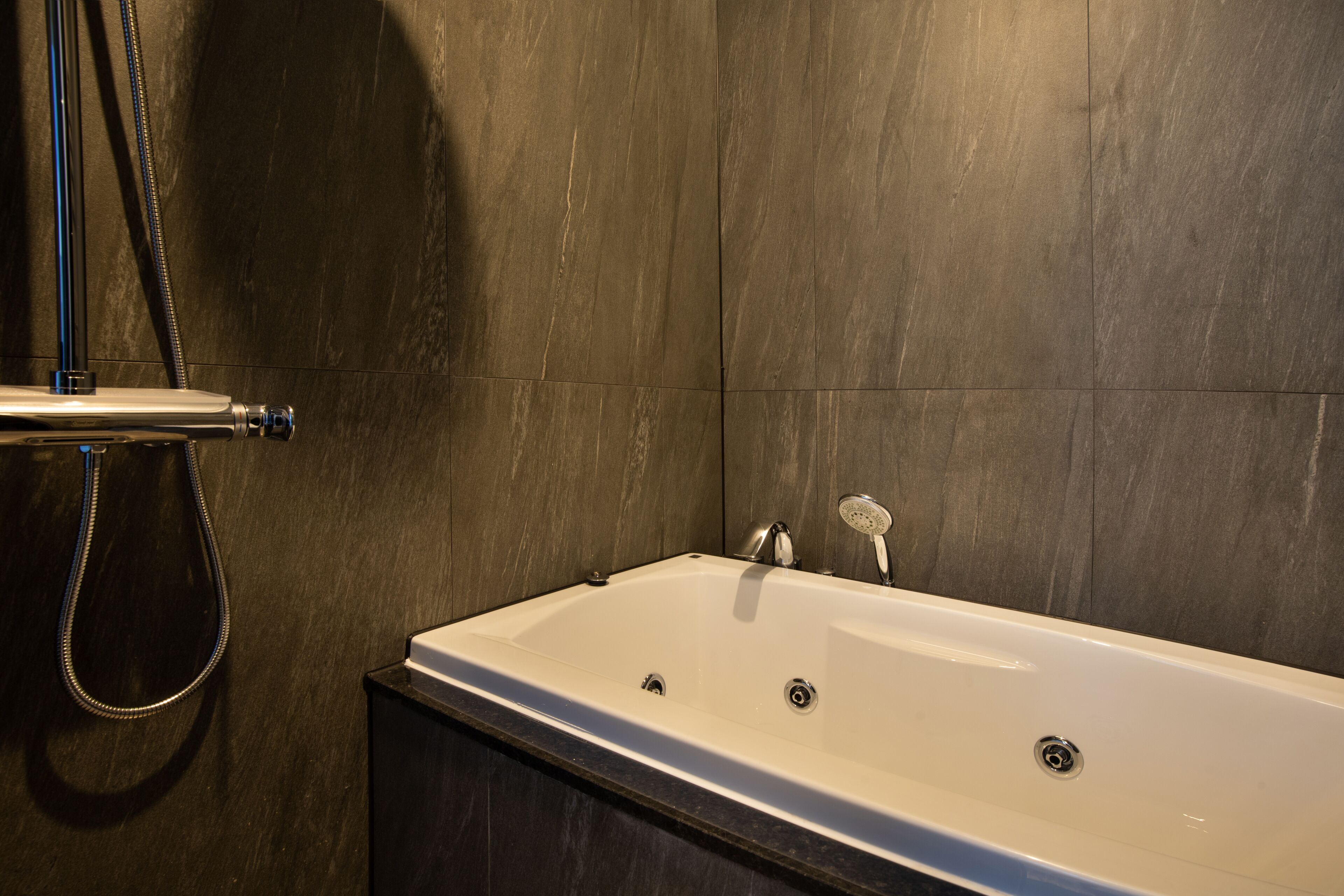 Un baño moderno con bañera, ducha y perchero.