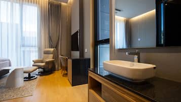 A modern bathroom with a large mirror, a white sink, and a wooden vanity.