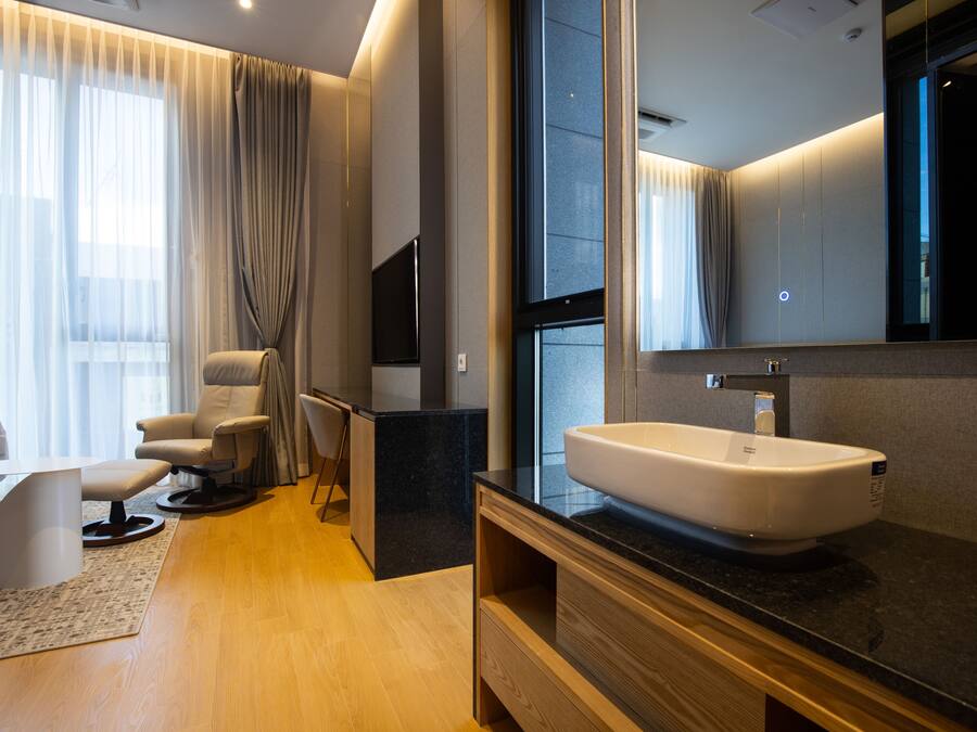A modern bathroom with a large mirror, a white sink, and a wooden vanity.