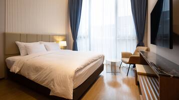 Una habitación de hotel moderna con una cama grande, un escritorio, una silla y un televisor montado en la pared.