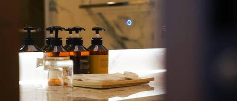 Una encimera de baño con varias botellas de jabón corporal y un vaso de agua.