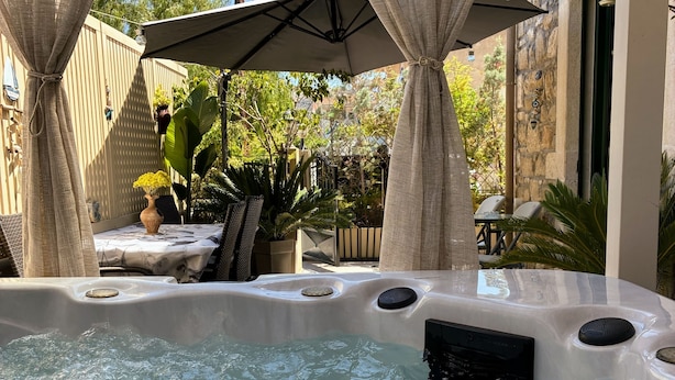 Un bain à remous offrant une vue dégagée sur l’eau, entouré d’une terrasse couverte agrémentée de chaises et de parasols.