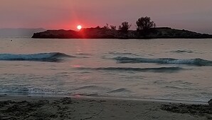 Une plage avec des vagues et un coucher de soleil en arrière-plan.