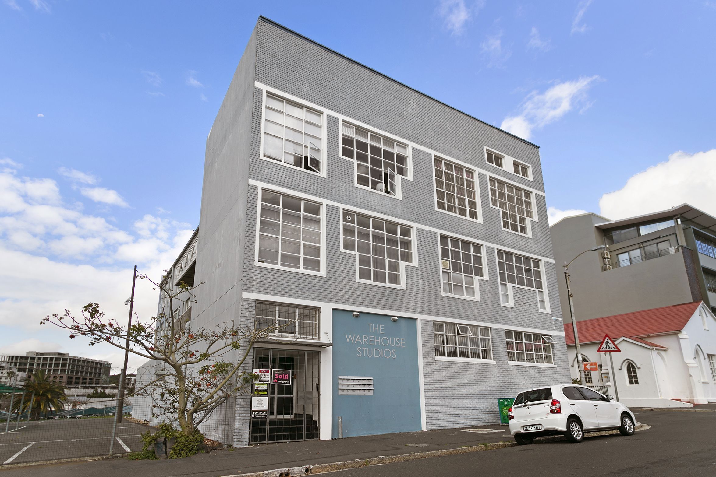 A multi-story building with a sign indicating 'The Warehouse Studios.'