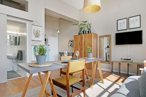 En moderne stue med spiseplads, møbler i træ og krukkeplanter.