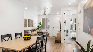 A dining area with a wooden table and chairs, a sofa with cushions, and a plant. - Stillwater #85 by RedAwning (St. George)
