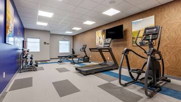 Un gimnasio equipado con cintas de correr, elípticas y una bicicleta estática.