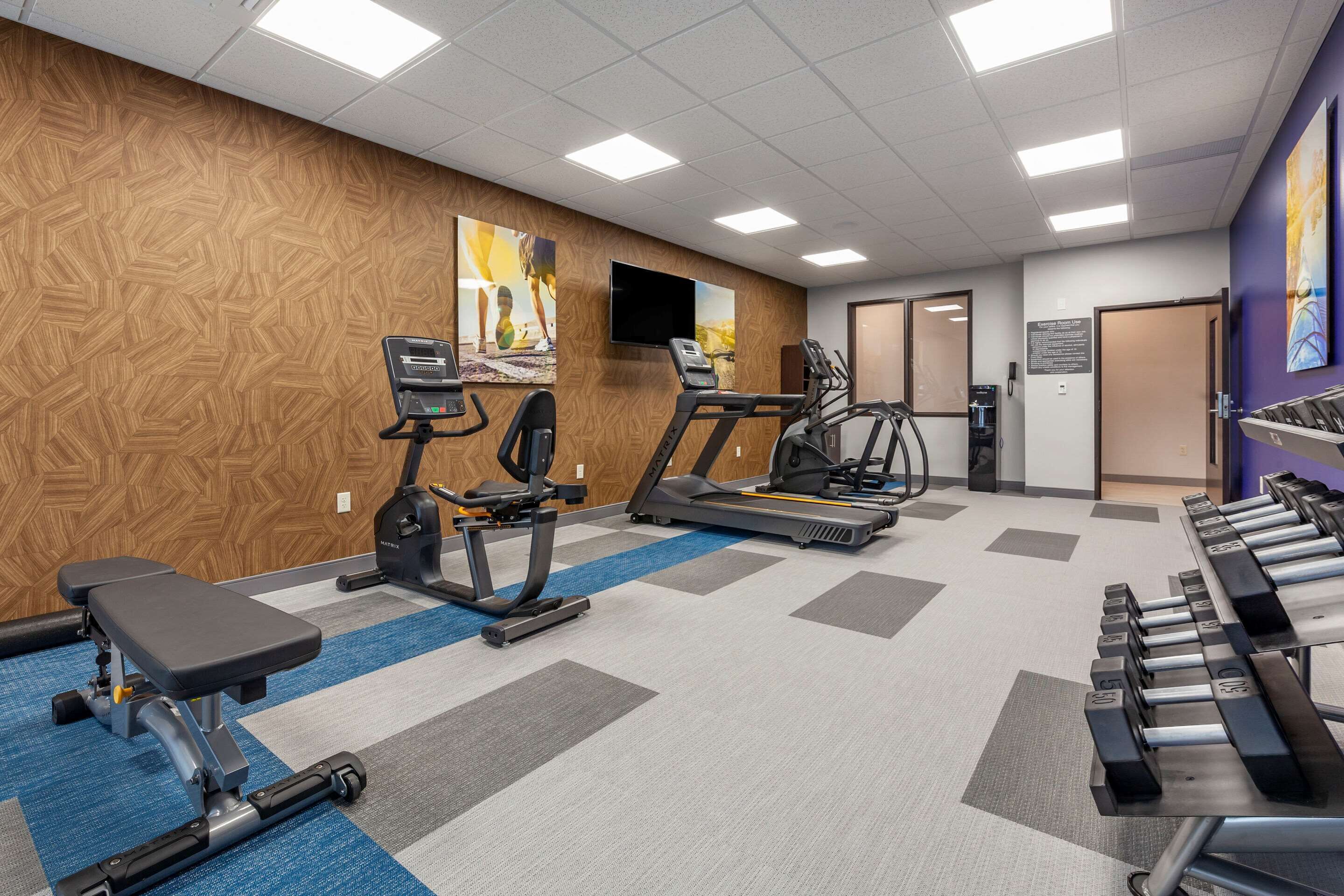 Un gimnasio con cintas de correr, elípticas y bancos de pesas.