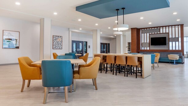 A spacious dining area with modern furniture and a large TV screen. - Comfort Suites Cottage Grove – Madison (Cottage Grove)