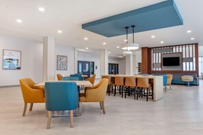 A spacious dining area with modern furniture and a large TV screen. - Comfort Suites Cottage Grove – Madison (Cottage Grove)
