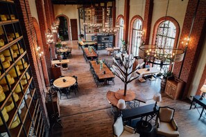Tilava ravintola, jossa on korkeat katot, paljaat tiiliseinät ja suuret ikkunat. Pöydät on sijoitettu rennosti, ja tarjolla on erilaisia istumavaihtoehtoja.