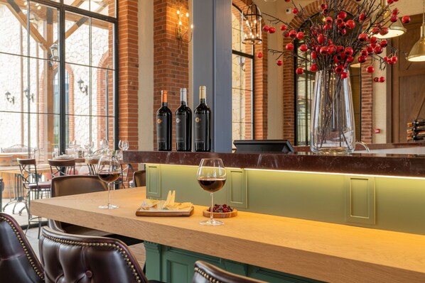 L’intérieur d’un restaurant avec un bar en bois, des fauteuils en cuir et une grande fenêtre.