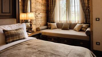 A cozy room with a large bed, a wooden bench, and a stone wall.
