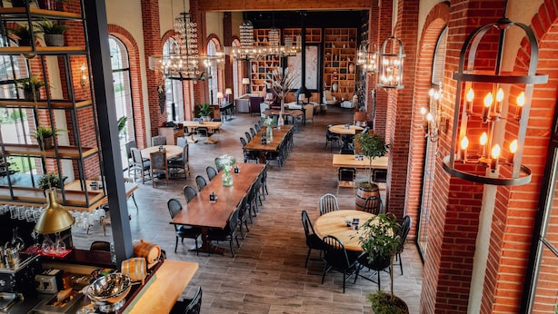 A spacious restaurant with brick walls, wooden tables, and hanging light fixtures. - Bengodi Boutique Hotel (Eceabat)