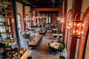 A spacious restaurant with brick walls, wooden tables, and hanging light fixtures. - Bengodi Boutique Hotel (Eceabat)
