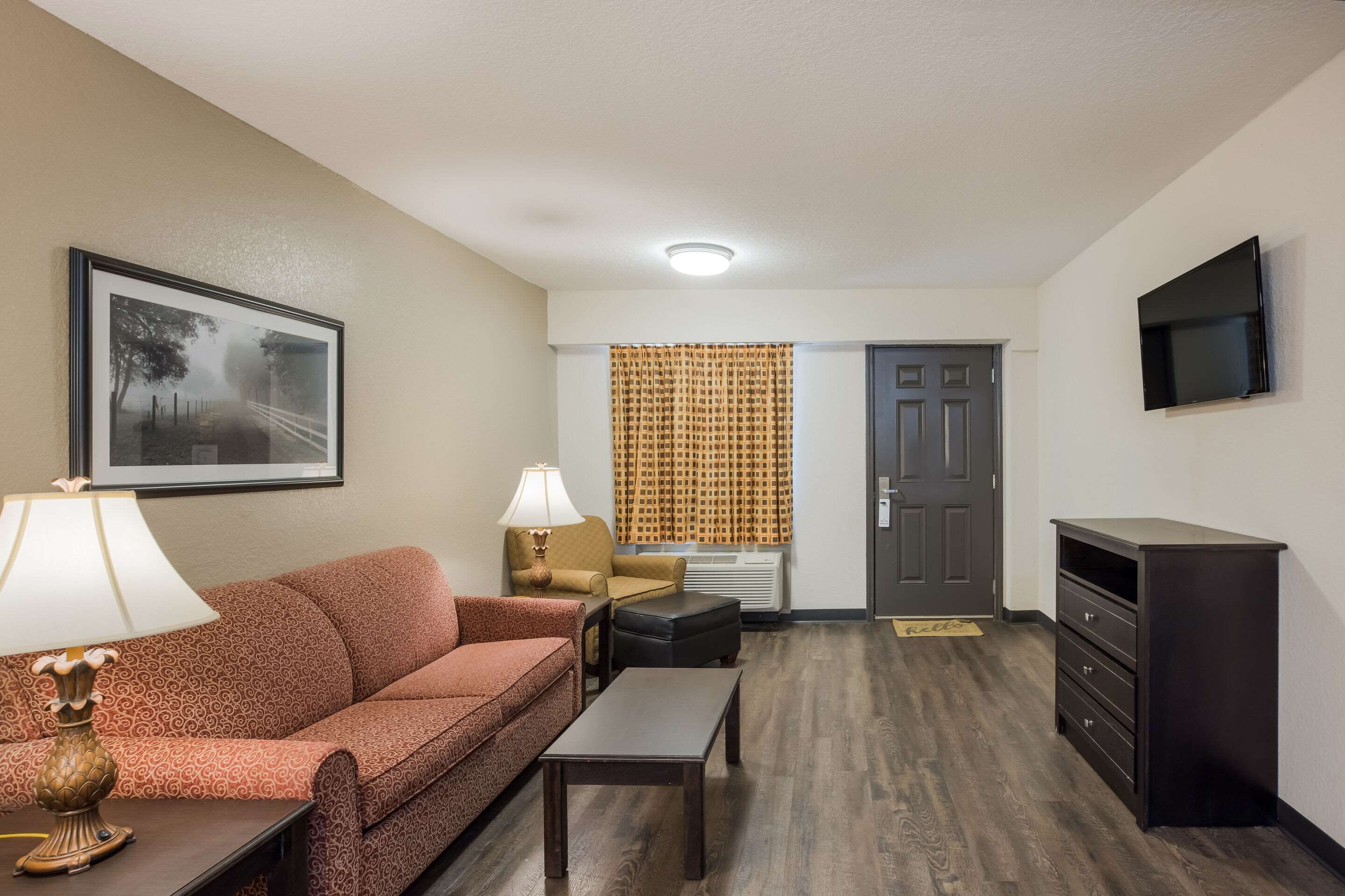 A furnished living room with a sofa, coffee table, lamp, and a television.