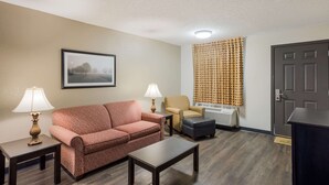 A living room with a sofa, two side tables with lamps, a coffee table, a chair, a small table, and a door. - Econo Lodge Vidalia (Vidalia)