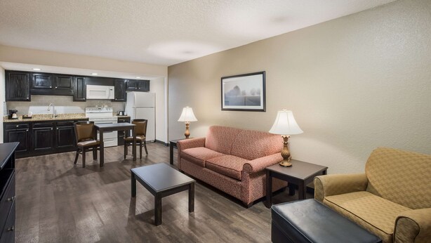 A living room with a sofa, a coffee table, and a dining area with a kitchen in the background. - Econo Lodge Vidalia (Vidalia)