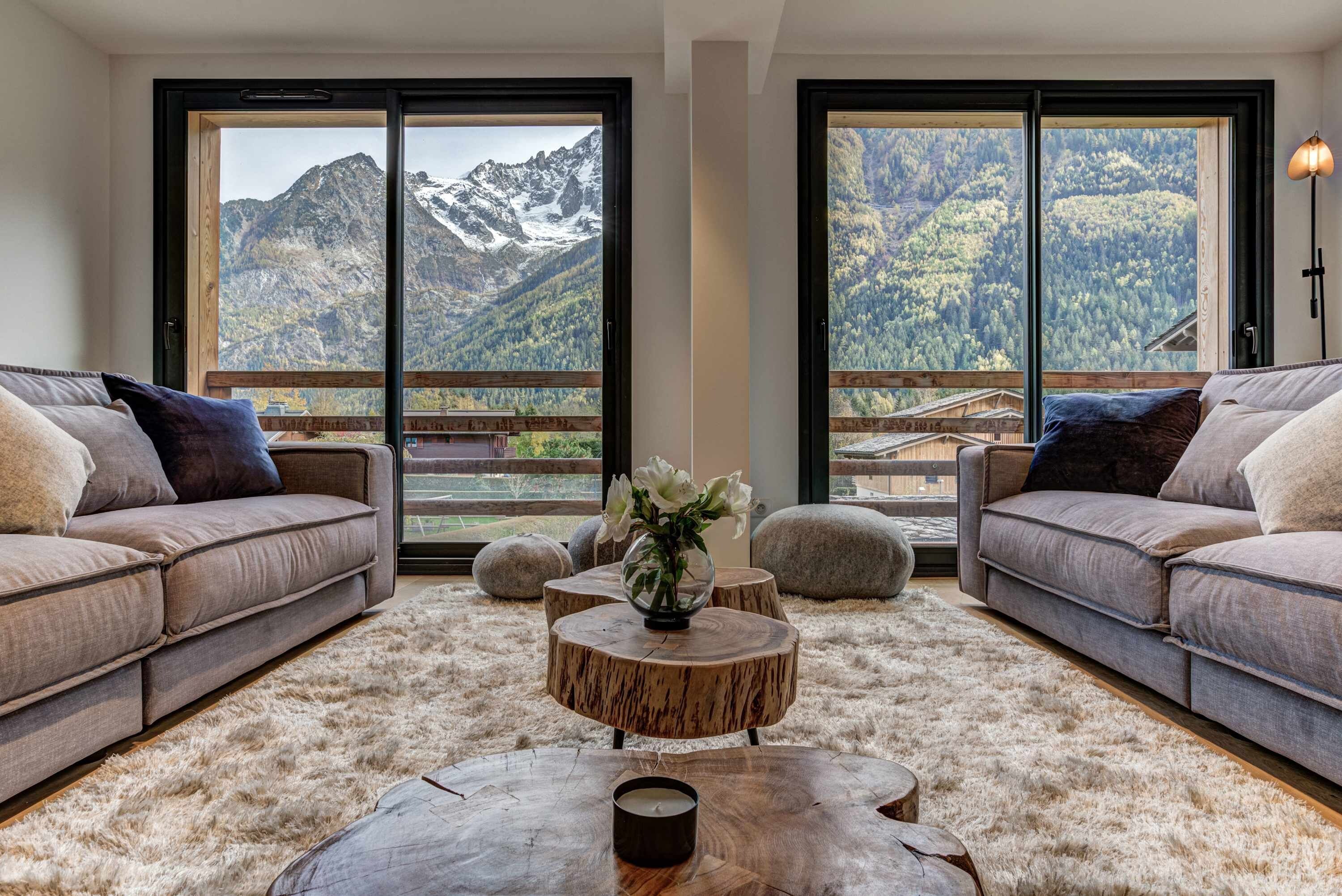 Un salon moderne avec deux canapés placés face à une grande fenêtre donnant sur un paysage montagneux.