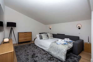 A modern bedroom with a bed, bedside tables, a lamp, and a wall-mounted light fixture. - Luxe La Cordee 221 penthouse - Chamonix All Year (Chamonix-Mont-Blanc)