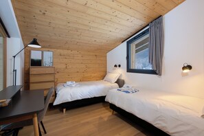 A compact bedroom with two beds, a desk, and a window with curtains. - Luxe La Cordee 221 penthouse - Chamonix All Year (Chamonix-Mont-Blanc)
