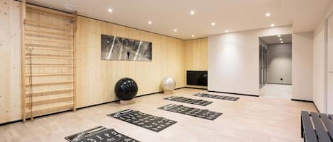 Un moderno spa con paredes de madera, un cuadro grande, colchonetas de ejercicio y un banco de madera.