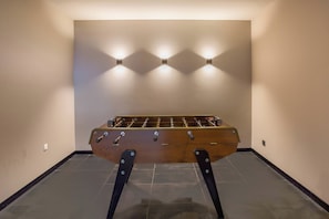 A foosball table in a room with tiled flooring and three wall-mounted lights. - Luxe La Cordee 221 penthouse - Chamonix All Year (Chamonix-Mont-Blanc)