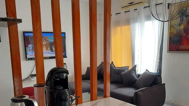 A modern living room with a sofa, coffee table, and a TV mounted on the wall. - Beautiful bright apartment in Dakar (Dakar)