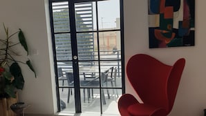 A modern interior with a red chair, a glass door leading outside, and a painting on the wall. - Beautiful bright apartment in Dakar (Dakar)