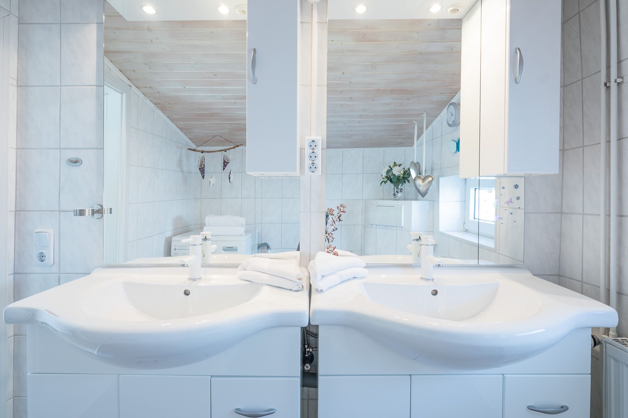 Een moderne badkamer met twee wastafels, een spiegel en een douche.