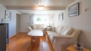 Ein geräumiges Wohnzimmer mit Holzboden, einem weißen Sofa, einem Couchtisch und einem Essbereich mit Tisch und Stühlen.