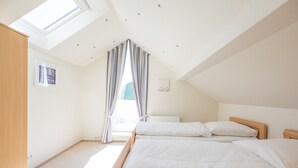 Ein Schlafzimmer mit zwei Betten, einem Oberlicht und einer Heizung.