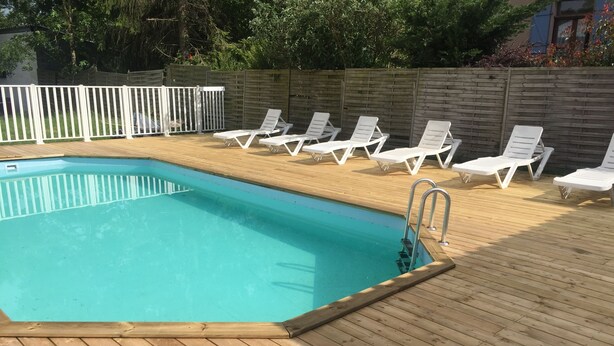 A rectangular swimming pool with a wooden deck and white lounge chairs. - Beautiful house in the country (LE FRAYSSE)