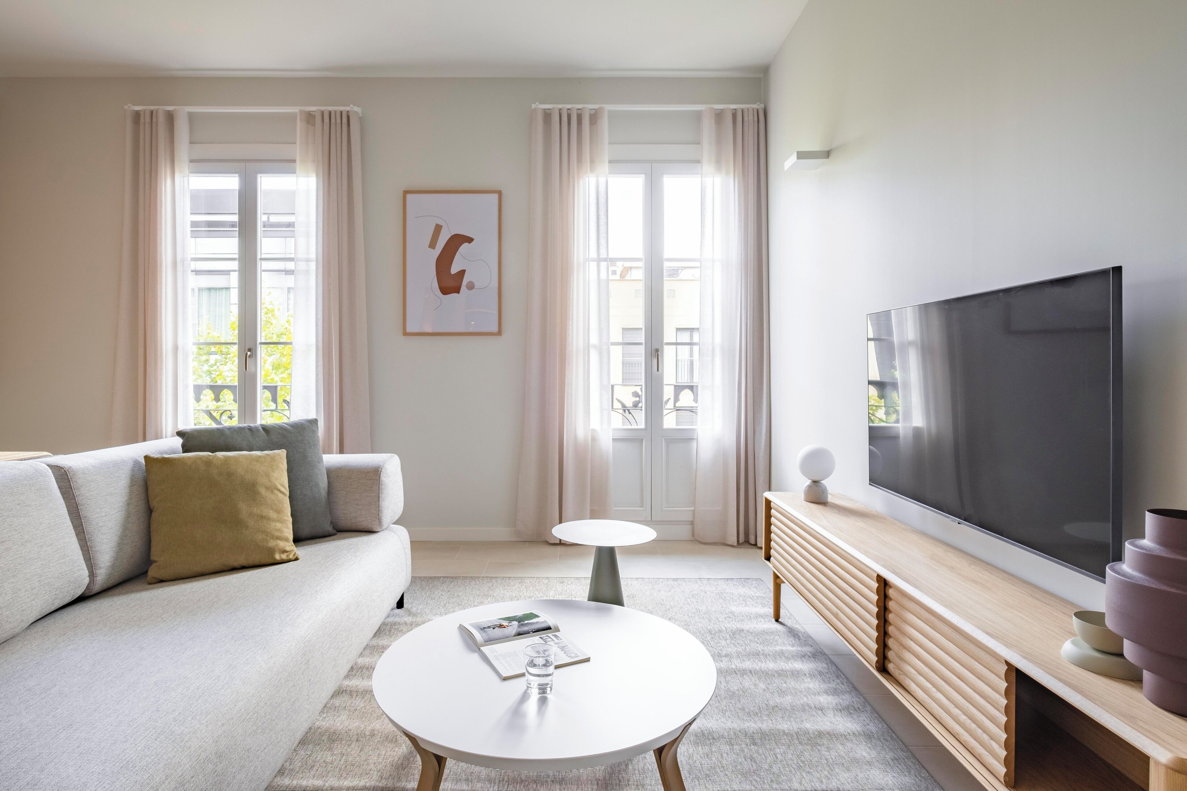 A modern living room with a sofa, a coffee table, a TV, and a painting on the wall.