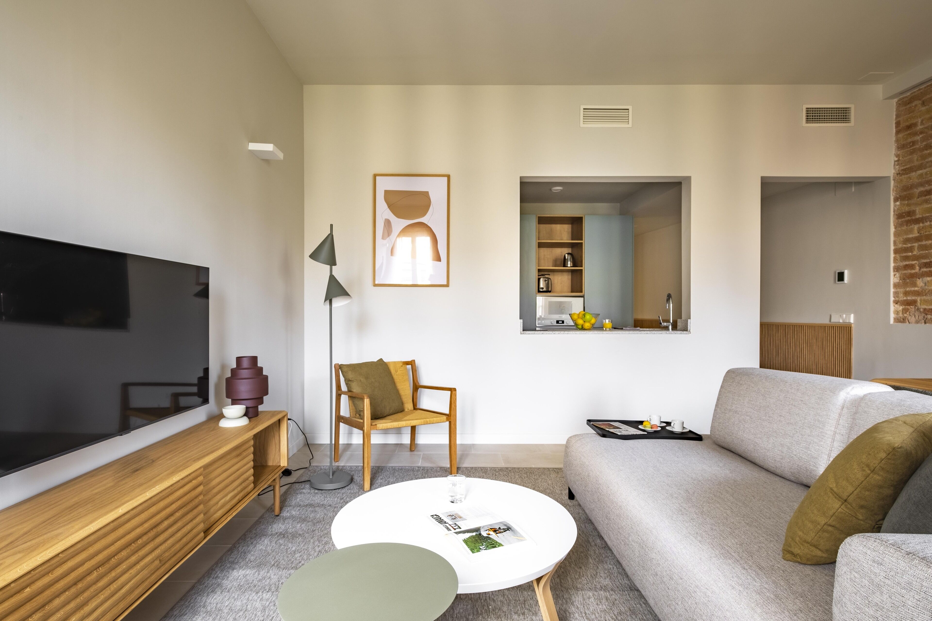 Una sala moderna con un televisor de pantalla plana, un sofá, una mesa de centro y un sillón.