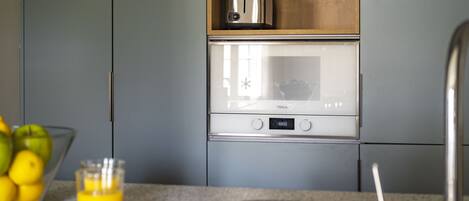 A kitchen with a microwave, toaster, and a bowl of fruit on the counter.