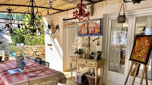 A sunlit room with a dining table, chairs, a desk, and an easel with a painting. - Charming artist's house. (Nîmes)