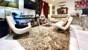 A modern living room with a flat-screen TV, a sofa, a chair, a coffee table, and a rug. - Charming artist's house. (Nîmes)