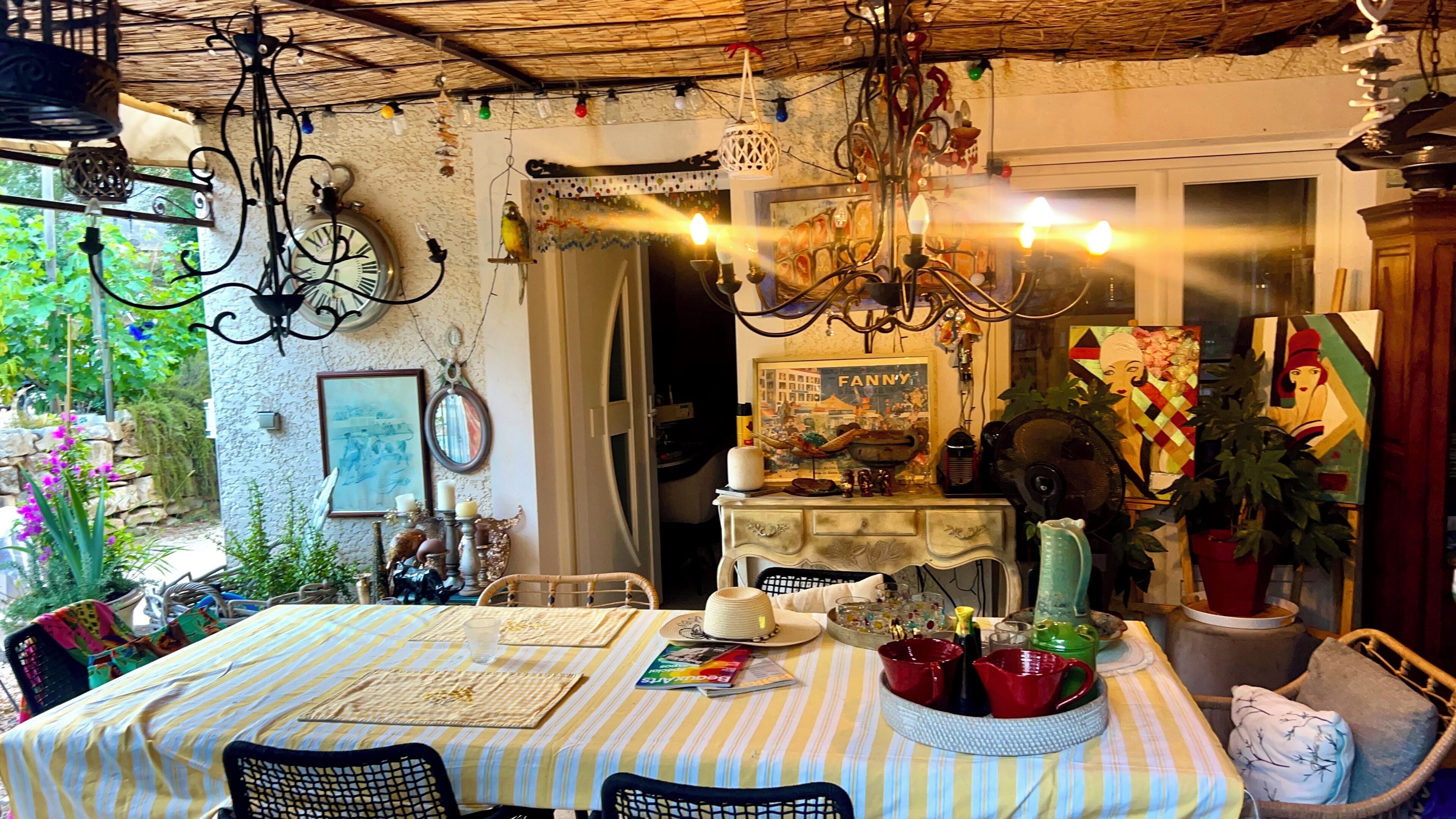 A dining area with a table set for two, a chandelier, and a view of the garden.