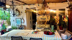 A dining area with a table set for two, a chandelier, and a view of the garden. - Charming artist's house. (Nîmes)