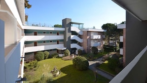 Un edificio a più piani con un cortile interno, caratterizzato da una fontana, immerso nel verde e con un cielo sereno.