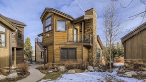 A modern two-story house with a stone facade, a balcony, and a visible garage. - Luxury 2 Bedroom Townhome Close to Main Street!! (Frisco)