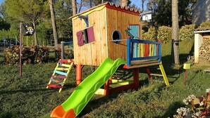 A wooden playhouse with a slide, a ladder, and a small door. - Modern air-conditioned villa, rated 4 stars+large heated swimming pool+beach volleyball court (Flayosc)